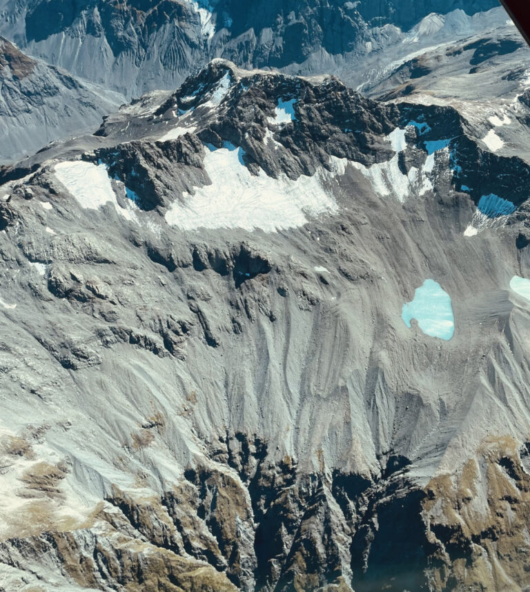 A grey mountain with large portions of its glacier melted away.