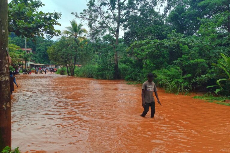 A man wades through knee-high orange water in Africa.