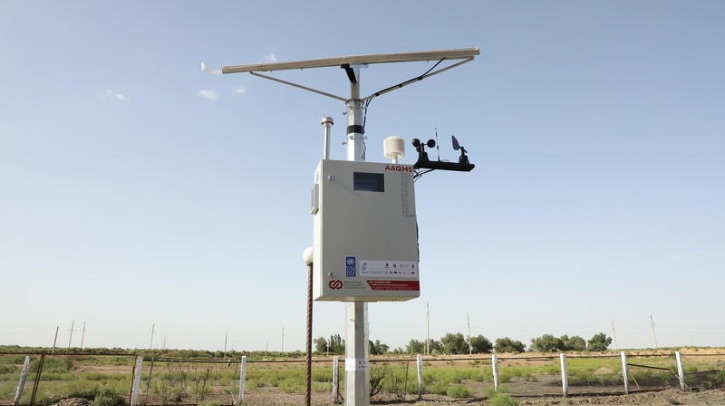 An automatic air quality monitoring stations stands against a clear blue sky.
