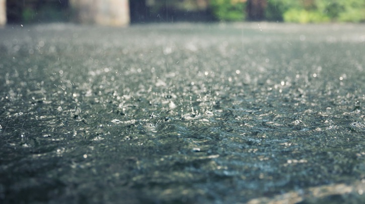 A close-up shows rain falling on tarmac.