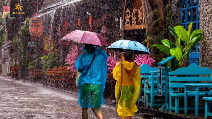 Two people walk down Yangshuo west street in the rain