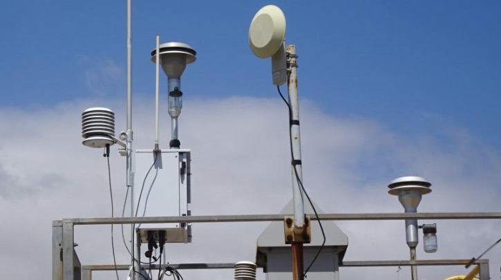 An air quality monitoring system reaches up to a blue sky.