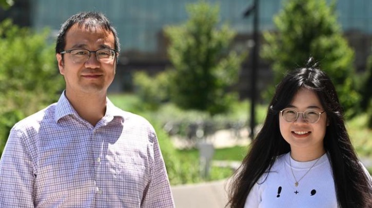 Two researchers smile into the camera against a garden backdrop.