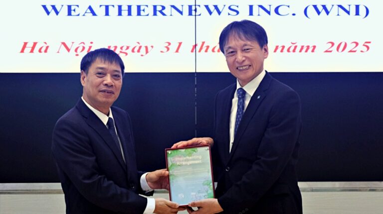 Vietnam Meteorological and Hydrological Administration's Hoang Duc Cuong and Weathernews Inc.'s Daisuke Abe shake hands at the signing of the MOU in front of a board displaying company logos.