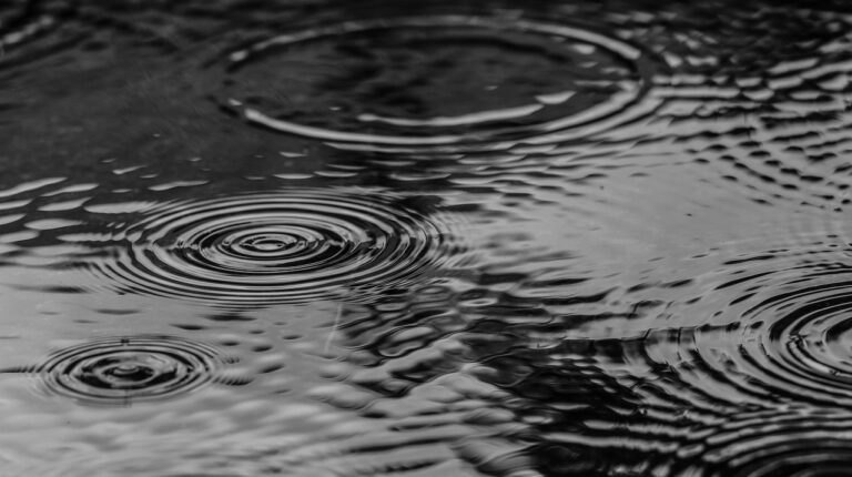 Close up of raindrops landing on the surface of a lake or puddle