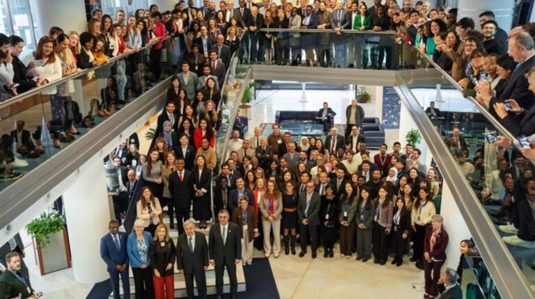 Group photo at the WMO Congress, with delegates standing together, some on the conference floor, some on stairs and some on the overlooking level above