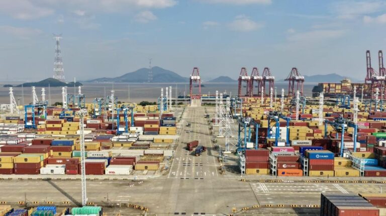 The Ningbo-Zhoushan Port in China, with stacks of containers, tall machinery and large wide roadways that meet at a junction in the middle
