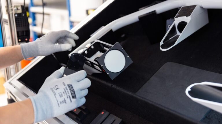 A Vaisala engineer wearing white protective work gloves handles a weather instrument as part of a maintenance project.