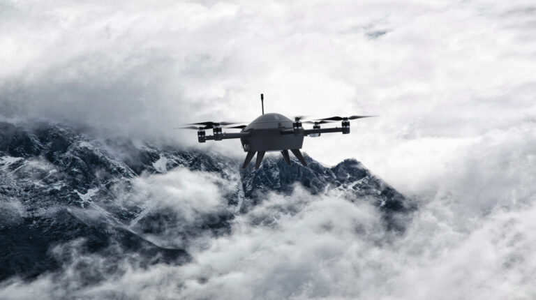 A meteorlogical drone flies through clouds around the top of a mountain.